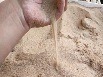 High angle view of person hand on sand