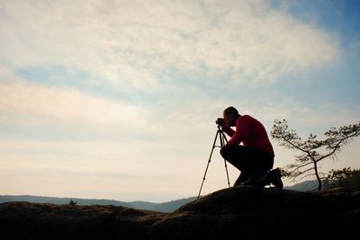 Amateur photographer takes photos with mirror camera on peak of rock. dreamy fogy landscape, 