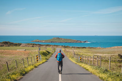 Rear view of woman walking on road against sky