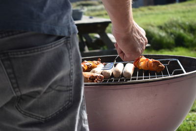 Midsection of person preparing food on barbecue grill