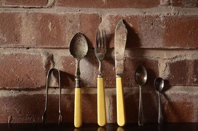 Close-up of old cutlery on table against brick wall