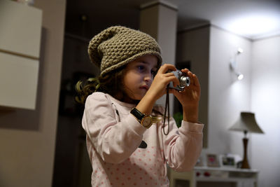 Girl photographing through camera at home