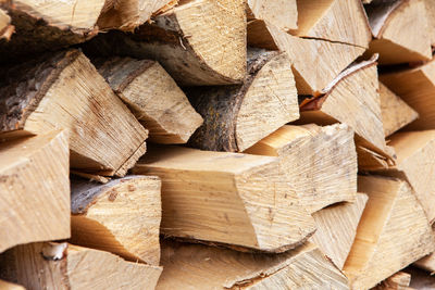 Background from stack of firewood from birch tree, for heating house, stacked in backyard, uncut