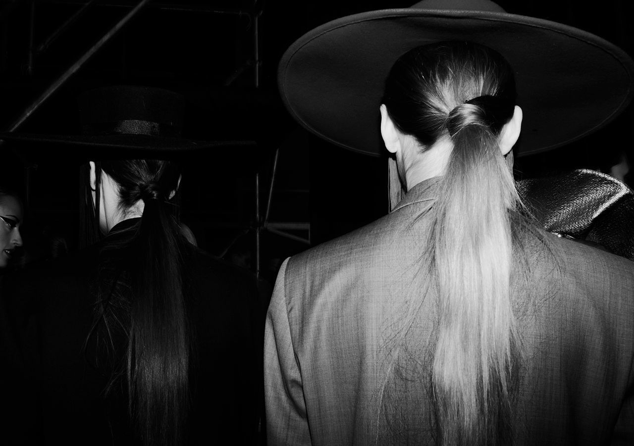 REAR VIEW PORTRAIT OF WOMAN STANDING IN CORRIDOR