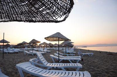 Lounge chairs and parasols on beach during sunset