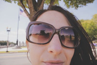 Close-up of woman with sunglasses against trees