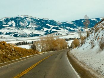 Road amidst snowcapped mountains against sky