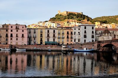 Buildings by river against sky in city