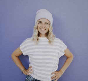 Portrait of young woman standing against blue background