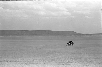 Man riding motorcycle on beach against sky