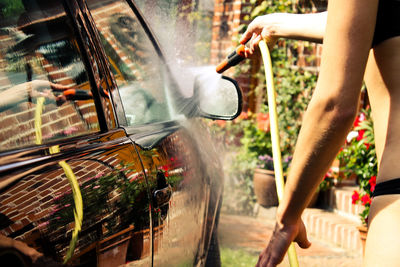 Midsection of woman washing car in back yard