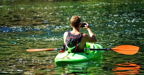 Rear view of man sitting on boat in lake