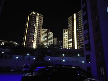 Cars on illuminated buildings in city at night