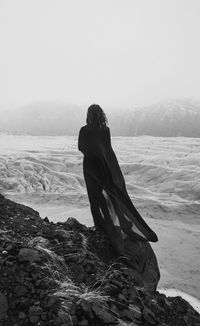 Woman with cape of chiffon on rock monochrome scenic photography