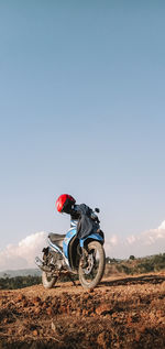 Person riding bicycle on field against sky