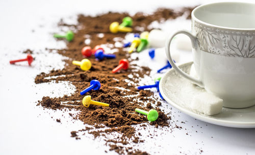 Close-up of coffee powder by cup and saucer on white table