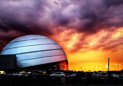 Cars on street against dramatic sky during sunset