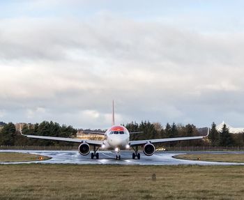 Airplane at airport runway against sky