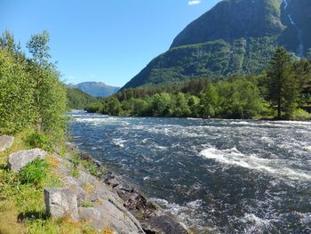 Scenic view of river by mountains against sky