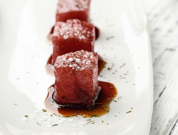 Tuna sashimi dipped in soy sauce, thick salt and dill on old white wooden board. raw fish.