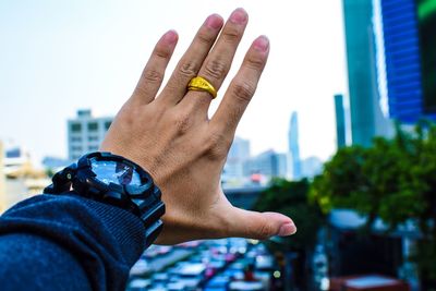 Close-up of human hand against sky