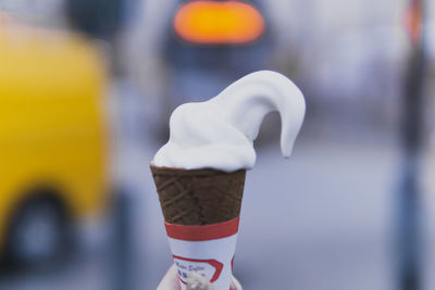 Cropped hand of woman having ice cream cone in city