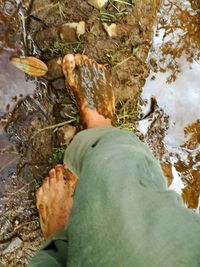 Low section of man standing on rock by water