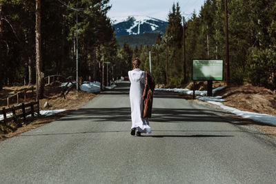 Man standing on road amidst trees