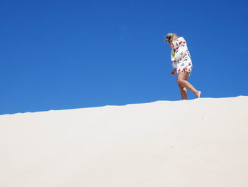 Low angle view of man on sand against clear sky