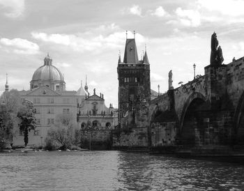 Charles bridge over vltava river in city against sky