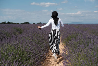 Cheerful woman running in lavender garden