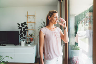 Side view of young woman standing at home