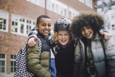 Portrait of happy friends standing together in front of school building