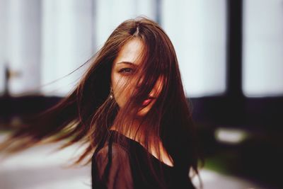 Portrait of mid adult woman with long hair shaking head while standing outdoors