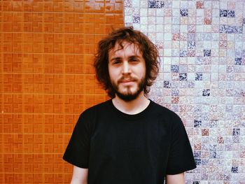 Portrait of young man standing against brick wall