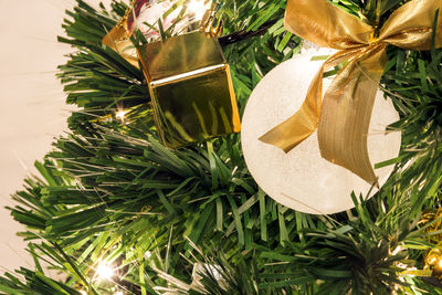 Close-up view of a christmas tree decorated with white balls and golden ribbons