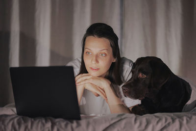 Young woman with dog lying on bed