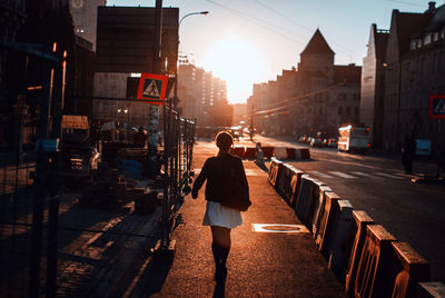 Rear view of man walking on street amidst buildings in city