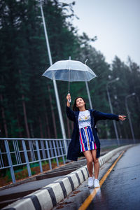 Full length of woman holding umbrella on rainy day