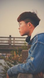 Side view of young man looking away against sky