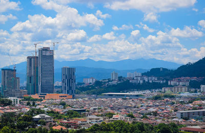 Aerial view of cityscape against cloudy sky