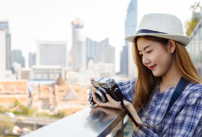 Young woman photographing with camera in city