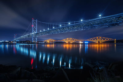 Illuminated bridge over river at night