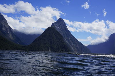 Scenic view of sea and mountains against blue sky