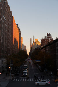 Traffic on city street and buildings against clear sky