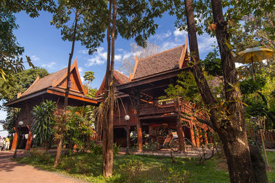 Gazebo by trees and building against sky