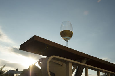 Low angle view of wine glass against sky during sunset