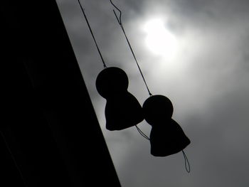 Low angle view of silhouette hanging against sky