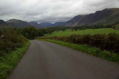 Road leading towards mountains against sky