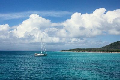 Boats in sea against cloudy sky